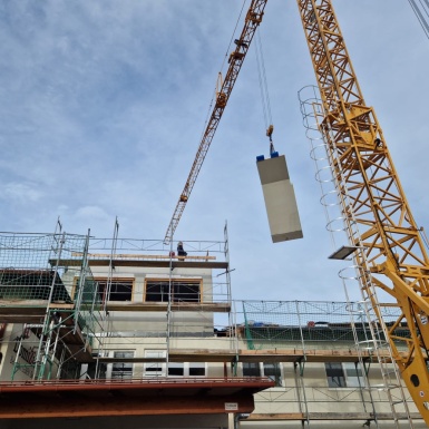 Baustellenkran hebt Betonstück auf das Dach