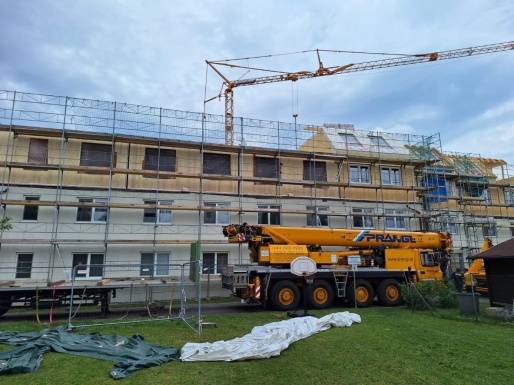 Wohnhaus mit Gerüst, Kran und Baufahrzeug