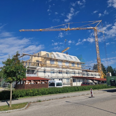 Haus mit Gerüst und Kran mit 2 neuen Stockwerken im Rohbau von weiter weg fotografiert