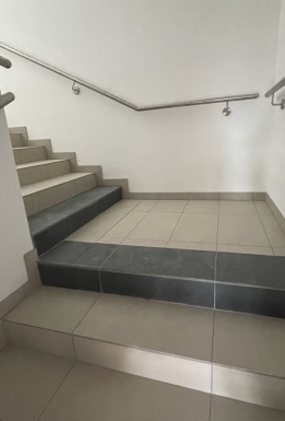 Beige und schwarze Treppen mit silbernen Treppenhandlauf und weißen Wänden