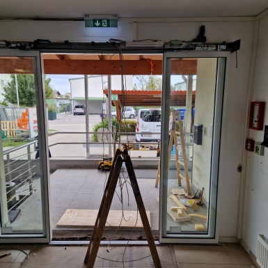 Leiter vor neuer Schiebetüre im Eingangsbereich der Baustelle