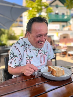 Mann sitzt bei Tisch und isst Mehlspeise
