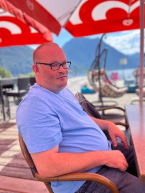Mann sitzt bei Tisch mit Sonnenschirm