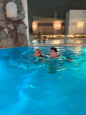 Zwei Frauen schwimmen in einem Pool im Innenbereich bei gedämpftem Licht