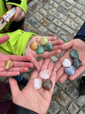 Vier Hände die bunte herzförmige Steine halten