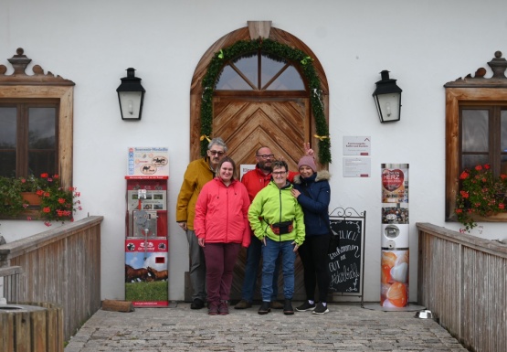 Menschengruppe steht vor weißem rustikalem Haus