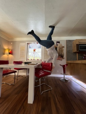 Frau ist in einem Raum der Illusionen der wie ein Esszimmer eingerichtet ist und steht auf der Decke
