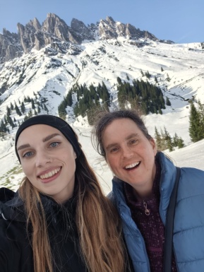 Zwei Frauen lachend mit einem schneebedecktem Berg im Hintergrund