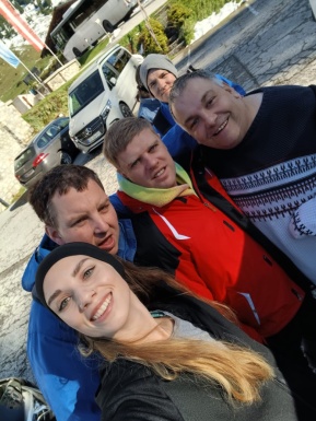 Gruppenfoto von einer Frau und vier Männern auf einem Parkplatz