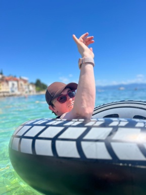 Frau im Schwimmreifen im Meer winkt