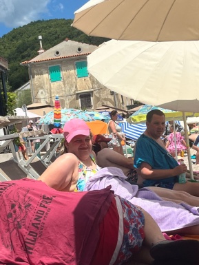 Menschen liegen am Strand unter Sonnenschirmen