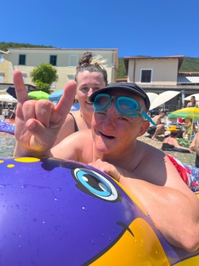 Mann mit Taucherbrille liegt auf Schwimmhilfe und freut sich