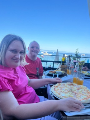 Frau und Mann sitzen beim Tisch mit Pizza und Getränken
