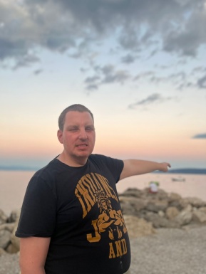 Mann am Strand zeigt aufs Meer
