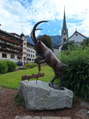 Hotel mit Steinbock Figur Wiese und einer Kirche
