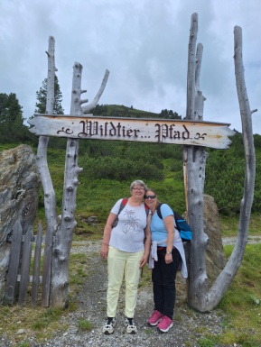 Zwei Frauen vor Baumstämmen mit der Aufschrift Wildtier Pfad