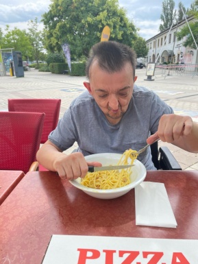 Mann bei Tisch isst Spaghetti