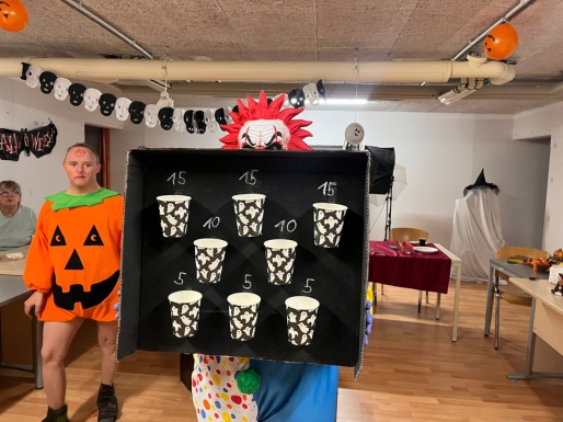 Maskierte Person hält Becherspiel in die Höhe