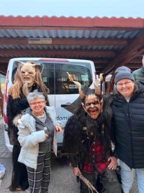 Zwei Frauen mit Personen die als Krampusse verkleidet sind