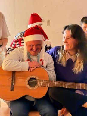 Mann mit Gitarre sitzt neben einer Frau und beide l&auml;cheln