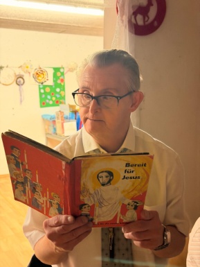 Mann mit Brille liest aus einem Buch vor