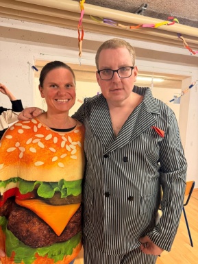 Frau als Burger verkleidet neben Mann mit Anzug