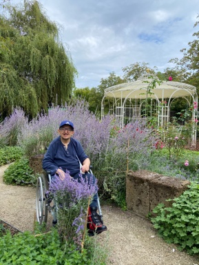 Mann im Rollstuhl in einem Garten mit Blumen