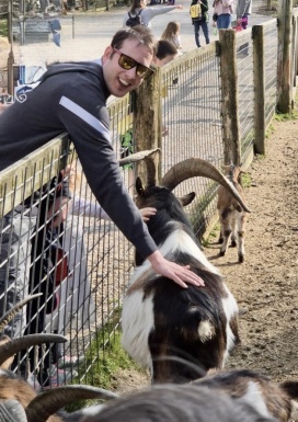 Mann mit Brille streichelt Ziege