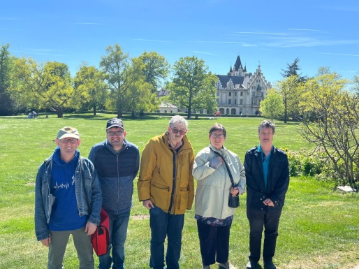 Gruppenfoto auf einer Wiese mit einem Schloss weiter weg im Hintergrund
