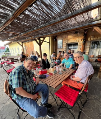 Gruppenfoto von Leuten die bei einem Tisch im &uuml;berdachten Au&szlig;enbereich eines Gastgartens sitzen