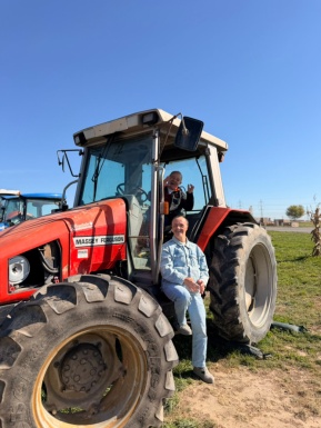 Ein gro&szlig;er Traktor in dem ein Mann sitzt und ein Mann steht daneben