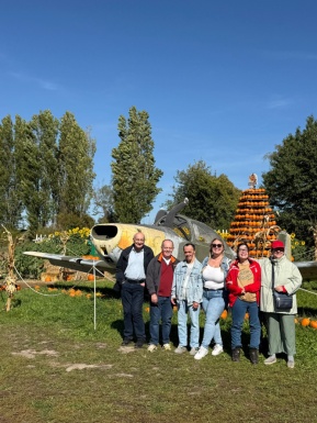 Gruppenfoto vor einem Modelflugzeug auf einer herbstlich dekorierten Landschaft