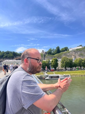 Mann von der Seite blickt auf das Wasser, Schiff und Himmel im Hintergrund
