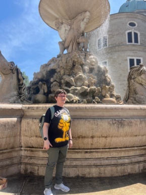 Frau mit Rucksack steht vor Springbrunnen