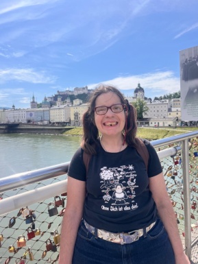 Frau lächelnd mit Brille auf Brücke Wasser und Stadt im Hintergrund