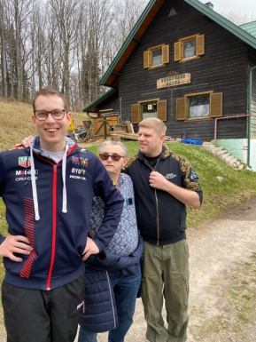 Drei Männer posieren vor einer Almhütte
