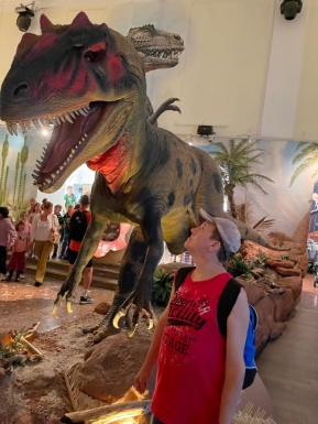 Mann schaut zu großer Dinosaurier Figur hoch