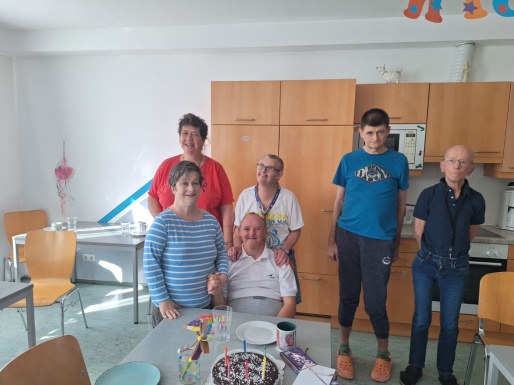 Gruppenfoto mit Geburtstagskind dass bei Tisch sitzt