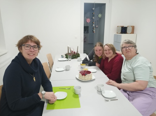Vier Frauen sitzen gemeinsam beim Tisch mit einer Torte