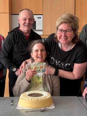 Frau legt Hand um eine Frau die vor einer Torte sitzt