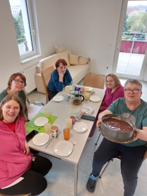 Gruppenbild von Frauen die beim Tisch sitzen mit einer Torte