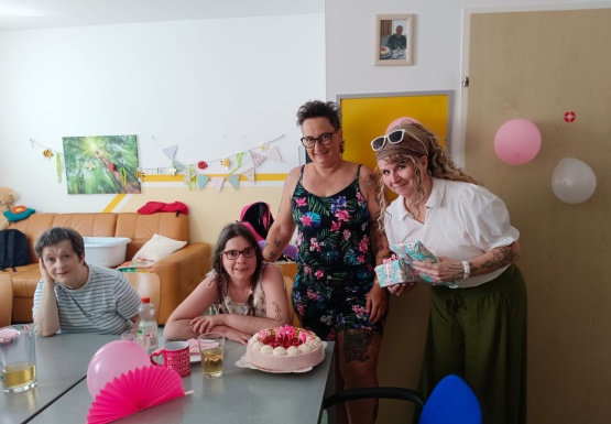 Gruppenfoto mit Geburtstagskind dass bei Tisch sitzt