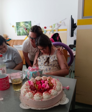 Frau gratuliert einer Mitbewohnerin zum Geburtstag und umarmt sie freundschaftlich