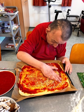 Mann beim Belegen einer Pizza