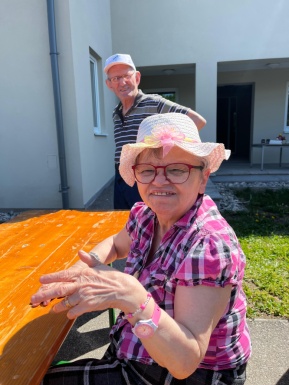 Frau mit Hut sitzend und Mann im Hintergrund stehend
