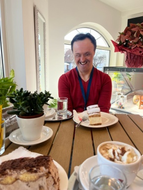 Mann sitzt mit Kuchen im Kaffeehaus