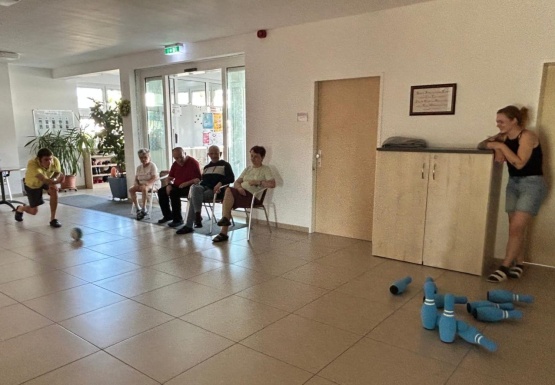 Personen sitzen und schauen Mann zu der eine Bowlingkugel rollt