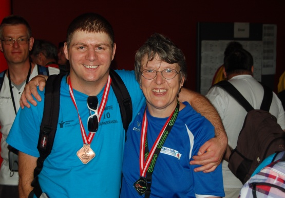 Mann und Frau mit Brille mit Medaille umarmen sich und lächeln