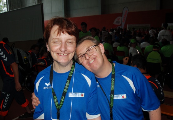 Mann mit Brille und Medaille legt den Arm um eine Frau mit Medaille und beide lächeln