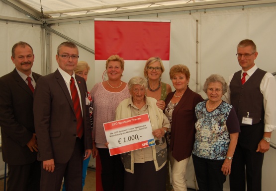 Gruppenfoto mit drei Männern im Anzug und der SPÖ Frauenrunde Spratzern die einen Spendenscheck im Wert von 1.000 Euro in Händen hält
